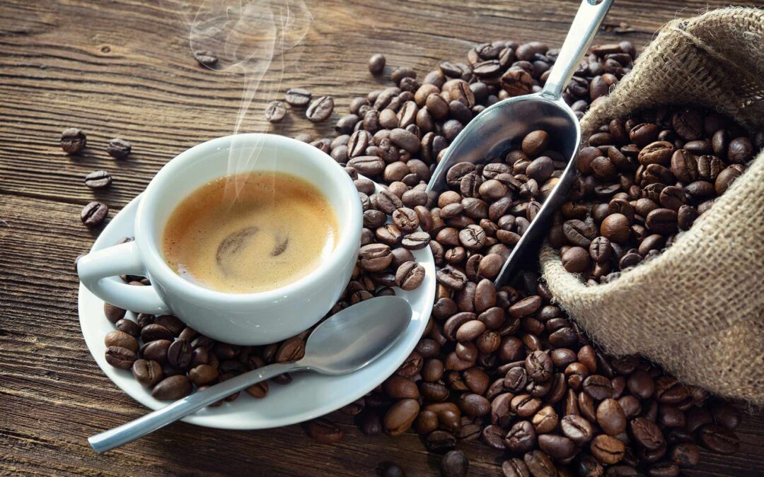 This is a picture of whole coffee beans spilling out of a bag, with a mug of coffee among it