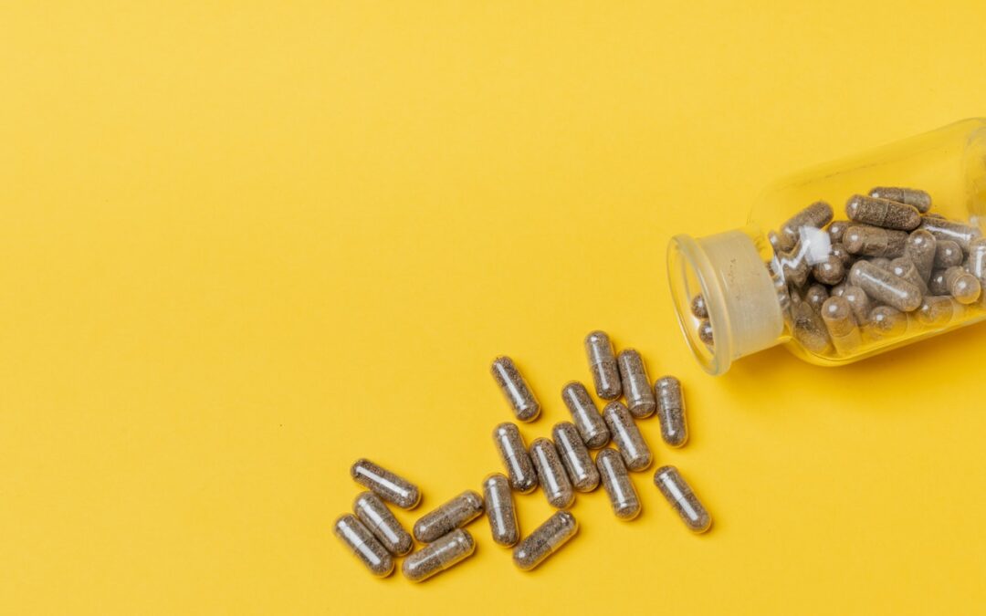 Supplements poured out of a glass bottle